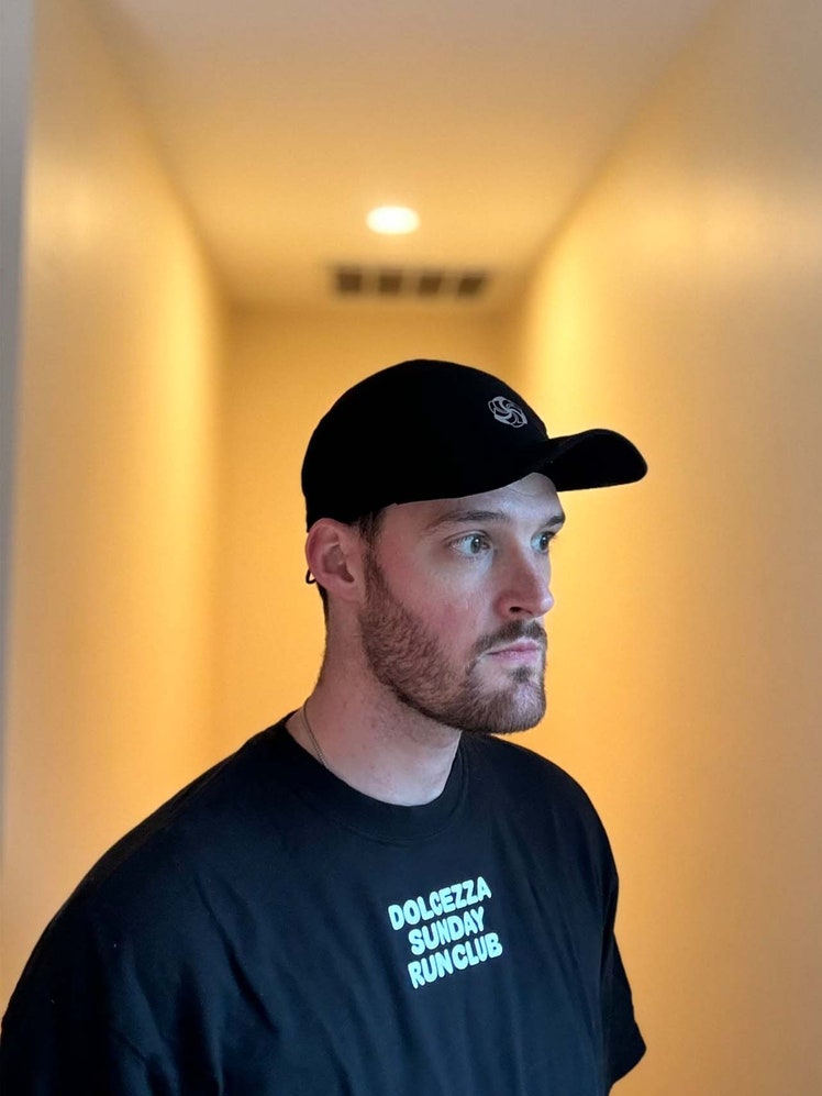 Image may contain: Cap, Clothing, Hat, Adult, Person, Baseball Cap, Head, Face, Sleeve, Crew Cut, and Hair